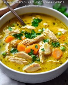 a bowl of chicken soup with carrots, celery and parsley in it