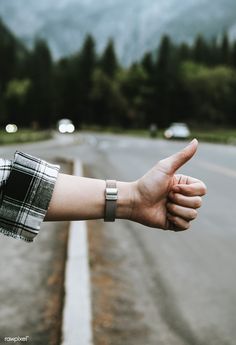 a person's arm with a wristband on the side of an empty road