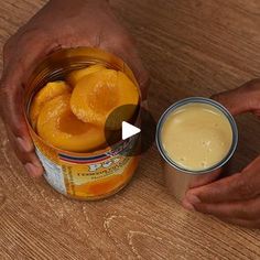 two hands holding an open can of oranges next to a jar of yogurt