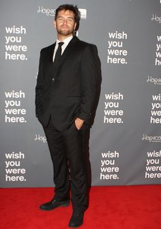 a man in a suit and tie standing on a red carpet with the words wish you were here