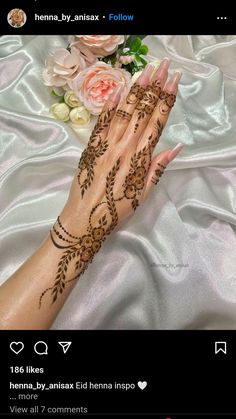 a woman's hand with henna tattoos on it and flowers in the background