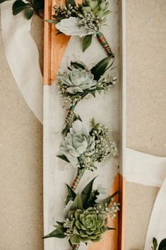 succulents and greenery are arranged in a row on a wooden board