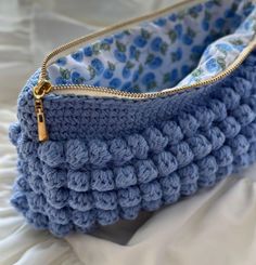 a blue crocheted purse with a gold zipper