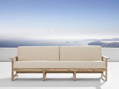 a couch sitting on top of a white floor next to a wall with an ocean view