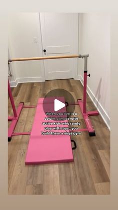 a pink exercise mat sitting on top of a wooden floor next to a metal bar