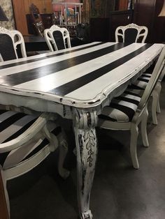 a dining room table with black and white stripes painted on the top, along with matching chairs