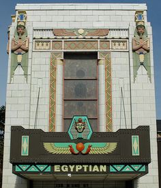 an egyptian theater sign on the side of a white brick building with blue and green accents