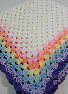 a multicolored crocheted blanket sitting on top of a white table