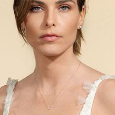 a close up of a woman wearing a white dress and necklace with feathers on it