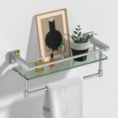 a bathroom shelf with a potted plant on it and a towel hanging from the wall