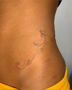 a woman with a tattoo on her stomach and lower back is shown from the waist up