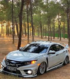 a silver car parked in the middle of a forest