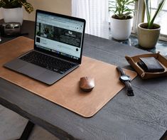 an open laptop computer sitting on top of a wooden desk next to a mouse pad