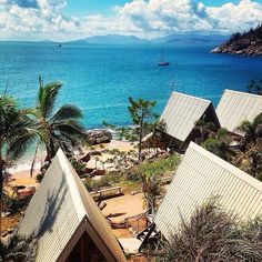 an aerial view of the beach and ocean with boats in the water, palm trees on either side