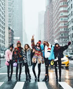 group of young women standing in the snow with their arms up and one holding an umbrella