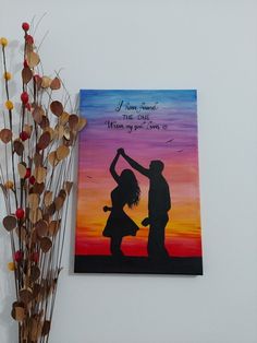 a painting on the wall next to a vase with dried flowers in it and a couple holding hands