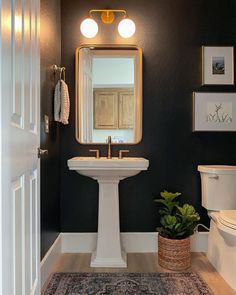 a bathroom with a sink, toilet and mirror in it's corner next to a door