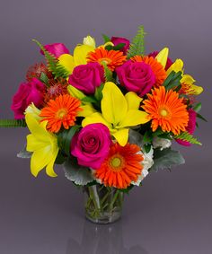 a vase filled with lots of colorful flowers on top of a gray table next to a wall