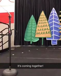 there is a stage set up with christmas trees on it and microphones in the foreground