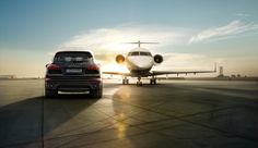 an suv parked in front of a large jet airliner on the tarmac at sunset