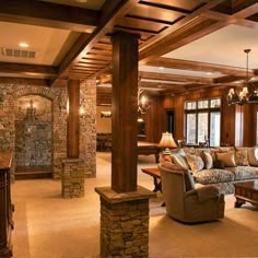 a living room filled with furniture next to a stone wall and ceiling mounted chandelier