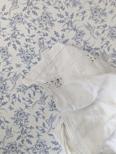 a pair of white pants laying on top of a blue and white floral print sheet