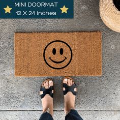 a person standing in front of a door mat with a smiley face drawn on it