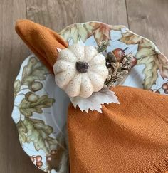 an orange napkin with a white flower on it sitting on top of a wooden table