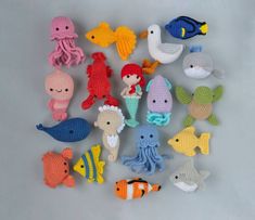 crocheted sea animals are displayed on a gray surface, including an octopus, fish, and squid