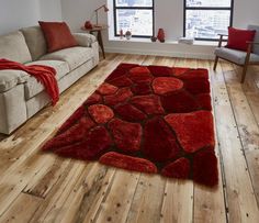 a living room filled with furniture and a red rug on top of a hard wood floor