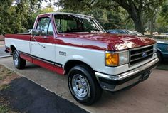 a red and white truck parked on the side of a road next to other cars