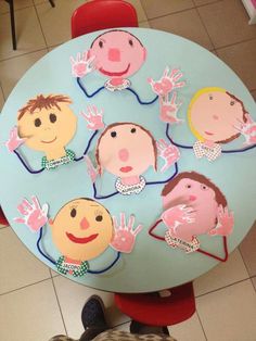 a child's table with paper cutouts of people on it and hands in the air