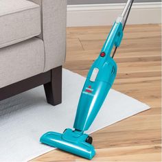 a blue vacuum is on the floor next to a couch