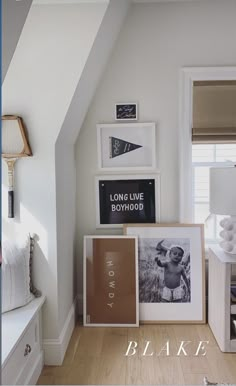 a bedroom with white walls and pictures on the wall, along with other decor items