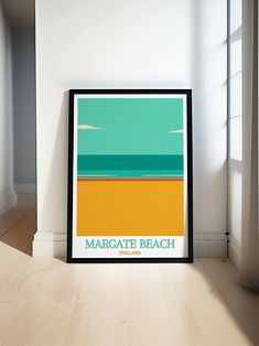 there is a framed poster on the floor in front of a window that reads margate beach