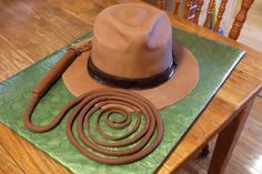 a brown hat and whip rope on top of a green tableclothed placemat