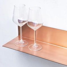 two wine glasses sitting on top of a metal shelf