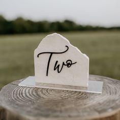 a piece of paper with the word two on it sitting on top of a tree stump