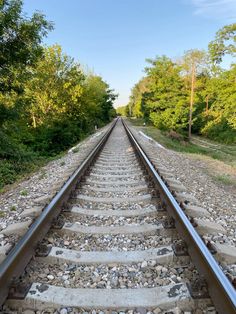 the railroad tracks are lined with stones and trees in the background, as if they were straight ahead