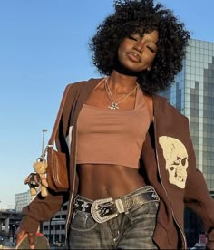 a woman standing in front of a tall building with her hand on her hip bag