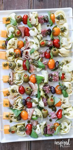 an appetizer platter with different types of food on skewers