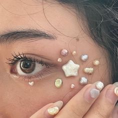 a close up of a person covering their face with shells and pearls on her eyes