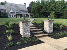 a stone house with steps leading up to the front door and landscaping area in front