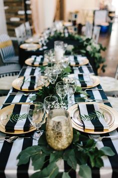 a long table with black and white striped runneres, greenery and gold place settings