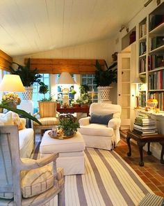 a living room filled with white furniture and lots of bookshelves on the wall