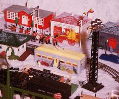 there are many toy trains and buildings on the tracks in front of a snow covered wall