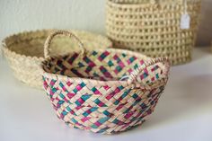 three woven baskets sitting on top of a white table next to each other with handles