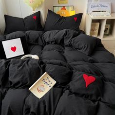 a black comforter with red hearts on it and a book laying on the bed