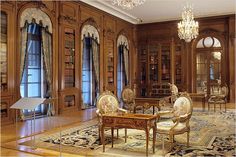 the room is full of antique furniture and bookshelves, with chandeliers hanging from the ceiling