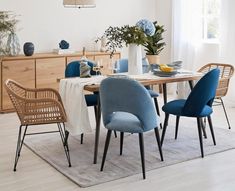 a dining room table with blue chairs and a white rug on the floor in front of it